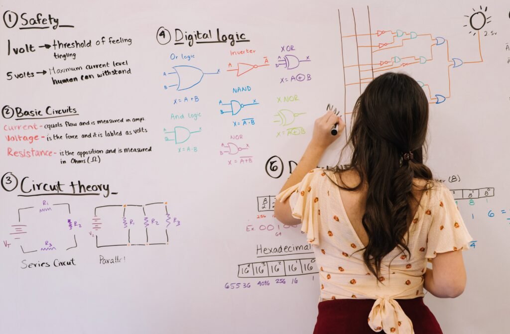 Teacher explaining circuits and logic gates on white board